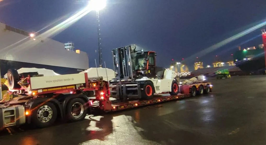 Nocny transport wózka widłowego na lawecie w porcie